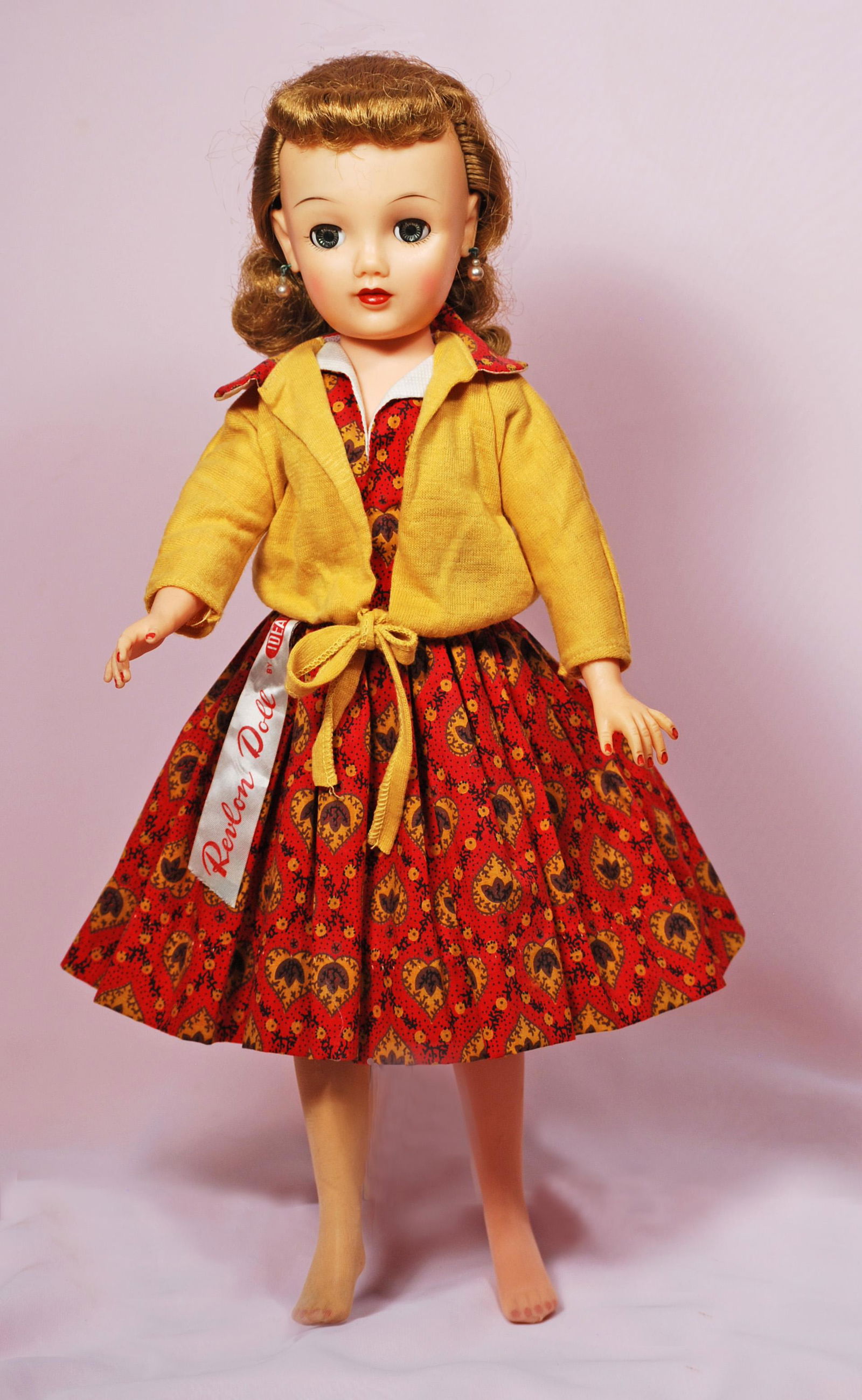 IDEAL 1957 MISS REVLON IN RED AND GOLD KNIT SWEATER: IDEAL 1957 MISS REVLON IN RED AND GOLD KNIT SWEATER. 20". Vinyl socket head, lady body with swivel waist, jointing at shoulders and hips, blue sleep eyes, painted lower lashes and feathered brows, clo