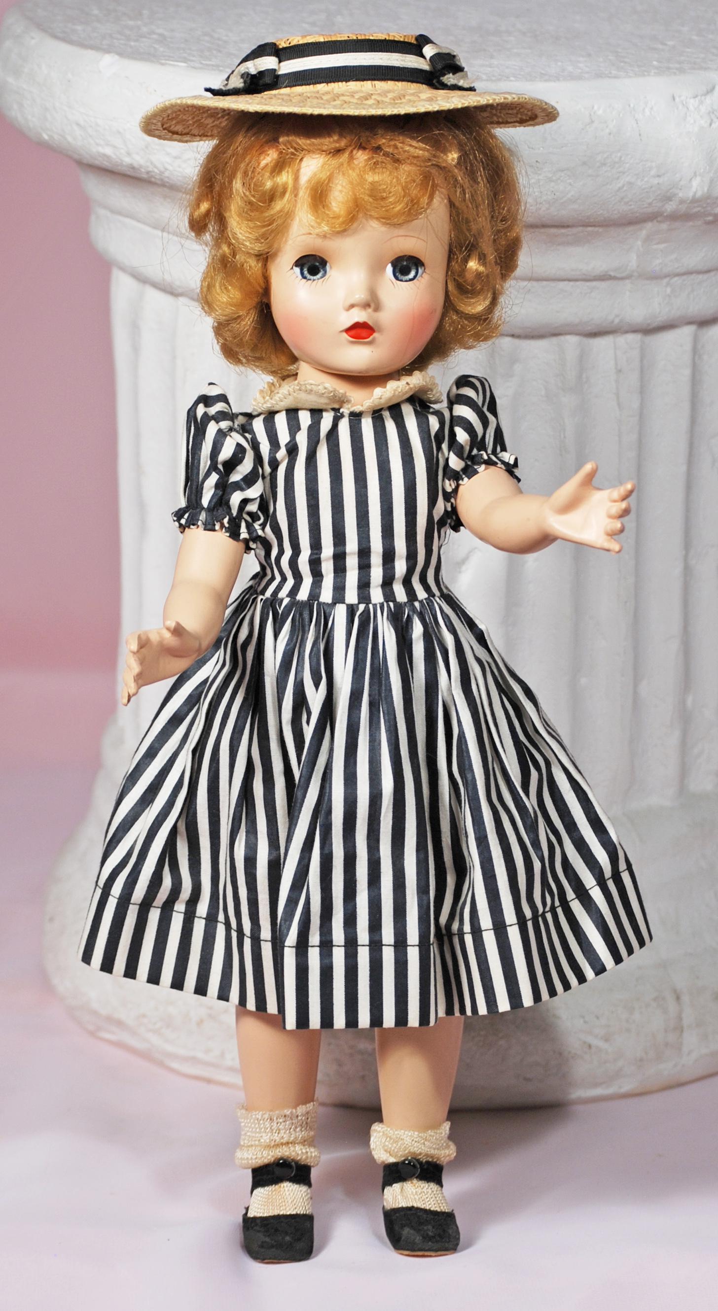 BINNIE WALKER IN BLACK AND WHITE STRIPED DRESS: BINNIE WALKER IN BLACK AND WHITE STRIPED DRESS. 15". Hard plastic socket head on walker body, blue sleep eyes, painted and applied lashes, ruby lips, blonde wig in original set, wears tagged black and