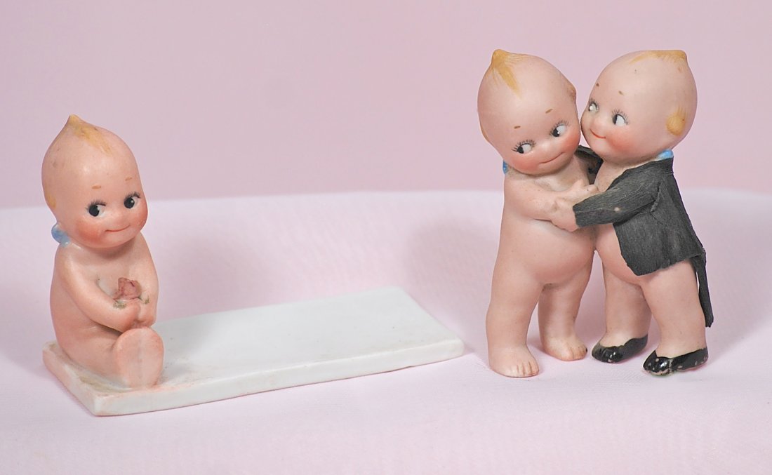 GERMAN BISQUE ROSE O’NEILL KEWPIE PLACE CARD & KEWPIE: GERMAN BISQUE ROSE OÂ’NEILL KEWPIE PLACE CARD & KEWPIE HUGGERS. 2 ¾Â” L. bisque place card holder features 2Â” H. seated Kewpie holding a pink rose, marked Â“cÂ” on bottom; 2 &fr