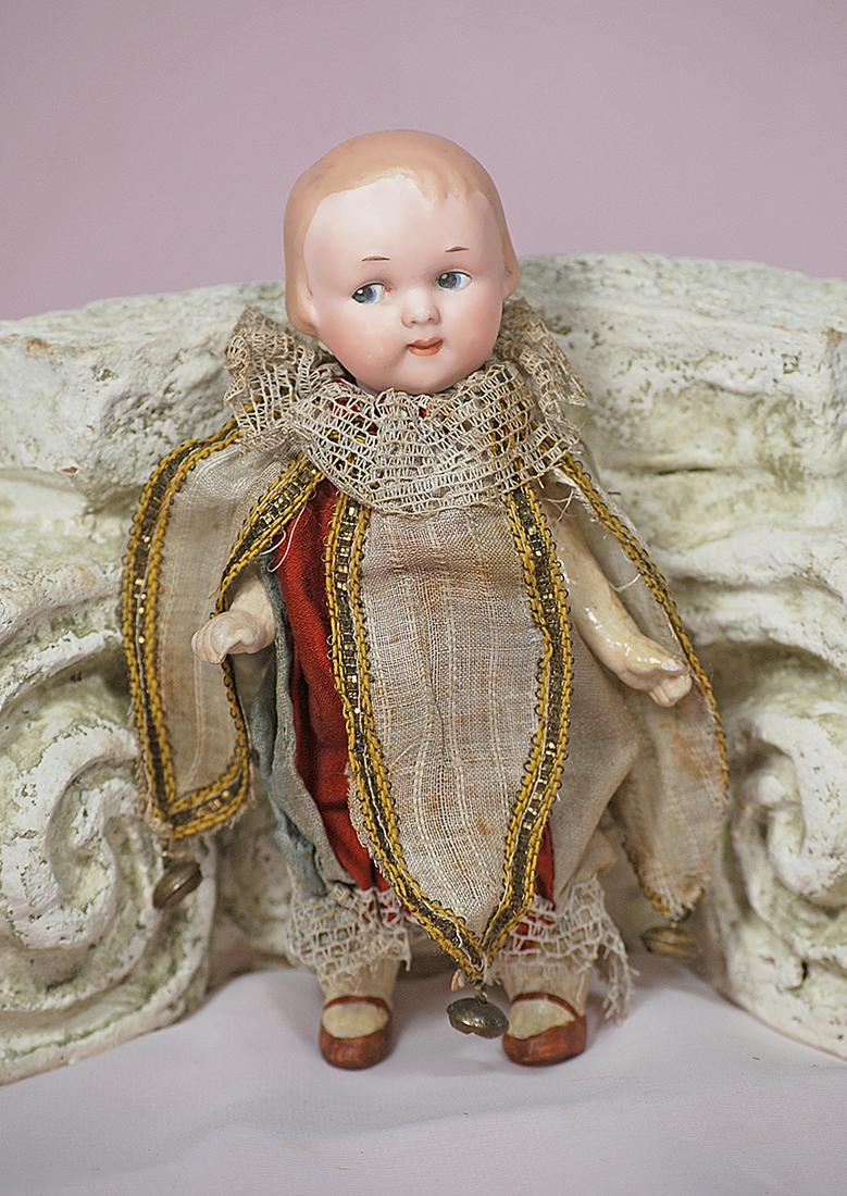 GERMAN BISQUE GOOGLY IN ORIGINAL JESTER COSTUME: GERMAN BISQUE GOOGLY IN ORIGINAL JESTER COSTUME. 7”. Marks: 210 A.10 M. Bisque socket head with sculpted brown hair, painted features, blue side glancing eyes, dash-type brows, closed mouth, accente