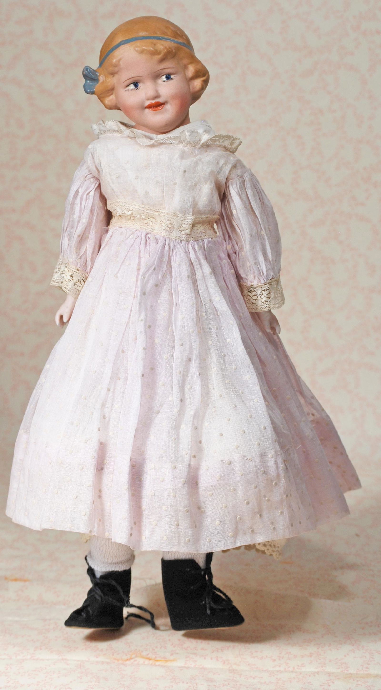 BISQUE COQUETTE BY DOLL POTTERY CO. OF ENGLAND: BISQUE COQUETTE BY DOLL POTTERY CO. OF ENGLAND. 14". Marks: DP Co. Bisque shoulderhead, sculpted hair with painted blue ribbon, painted features, side-glancing eyes, closed mouth with painted tiny tee