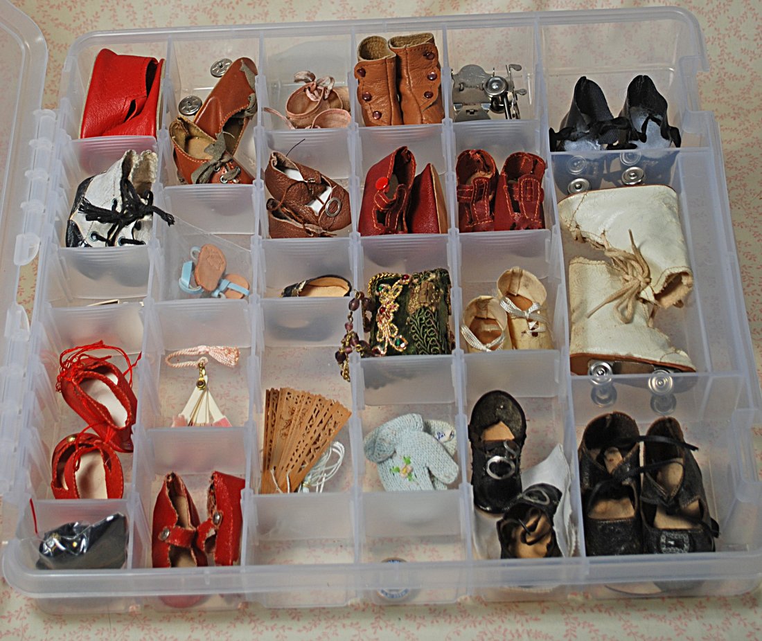 CASE OF DOLL SHOES AND ACCESSORY ITEMS.: 281.CASE OF DOLL SHOES & ACCESSORY ITEMS. 14" x 14" compartmented plastic case containing assortment of antique, vintage and contemporary doll footwear, purse, two fans, pair of mittens and Schoenhut 