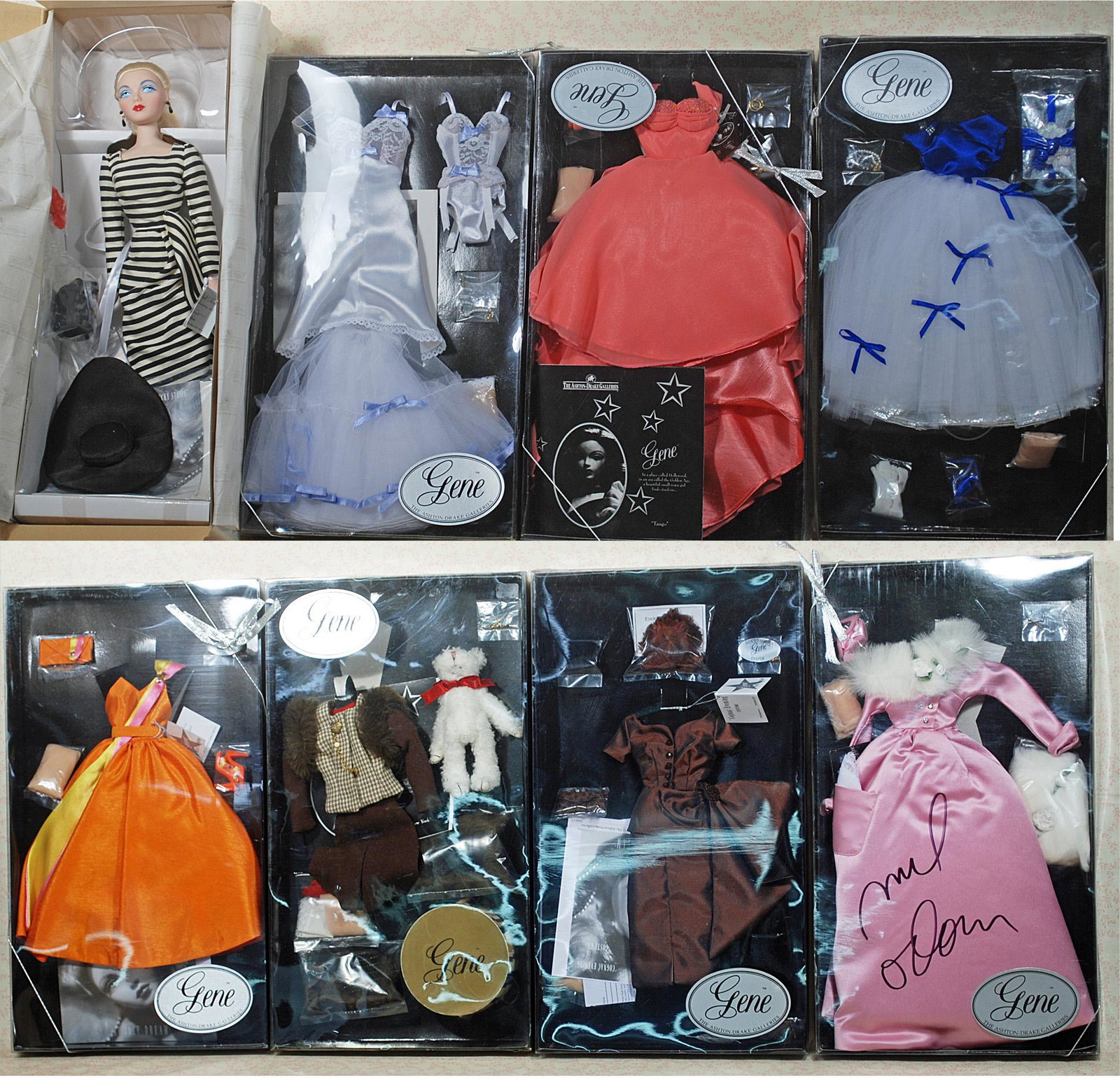 GENE FASHION DOLL BY ASHTON DRAKE WITH SEVEN ORIGINAL: GENE FASHION DOLL BY ASHTON DRAKE WITH SEVEN ORIGINAL COSTUMES. Gene Is 16" platinum blonde doll in original costume with accessories and box. Costumes include: Mel Odom Blossoms in the Snow, Goodbye 