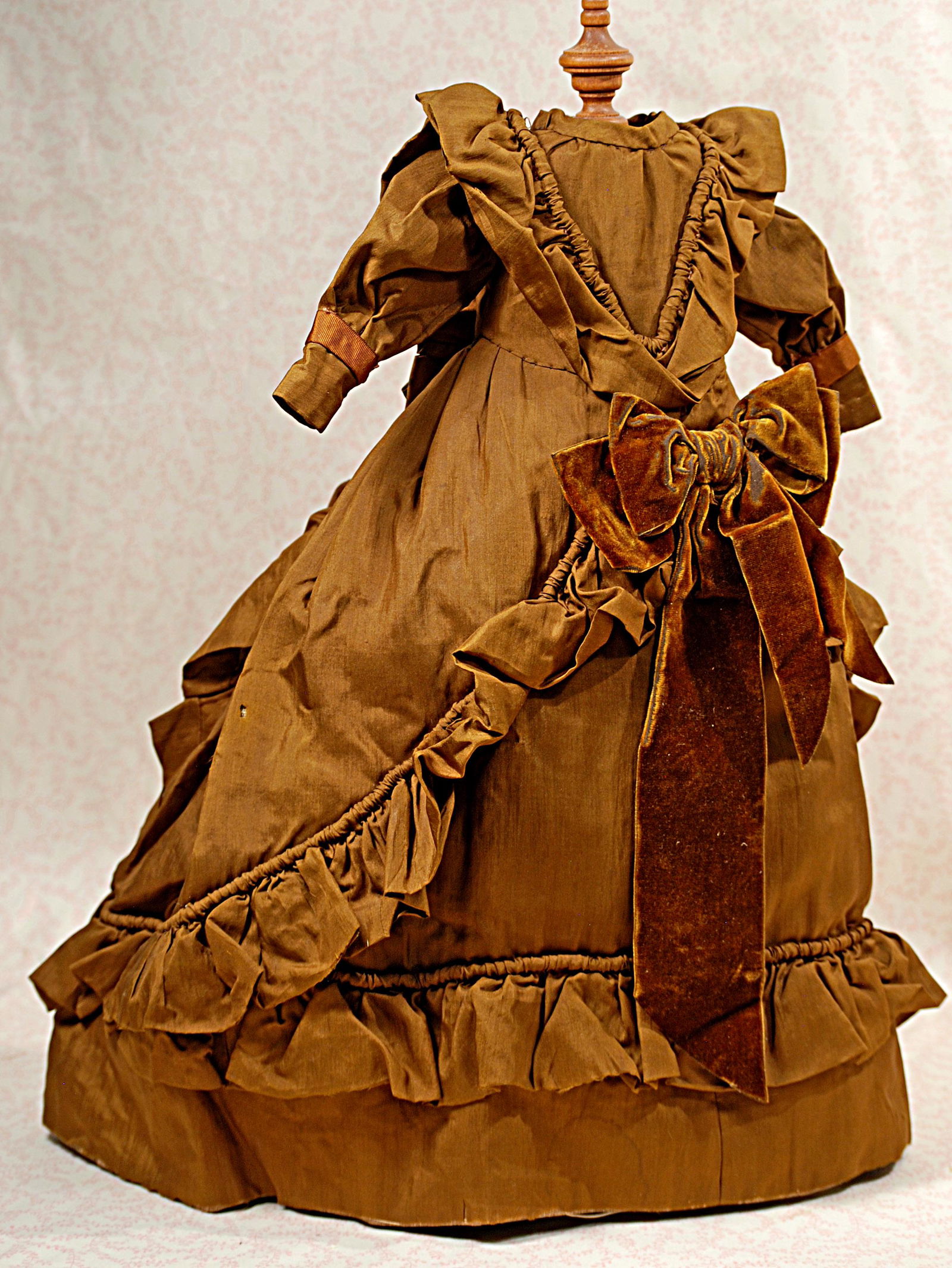 SILK GOWN FOR FASHION DOLL.: SILK GOWN FOR FASHION DOLL. Cocoa brown silk dress has fitted bodice with v-shaped ruffle accents front and back, puffed long sleeves, flared skirt with ruffled trim at sides and hem line, large brown