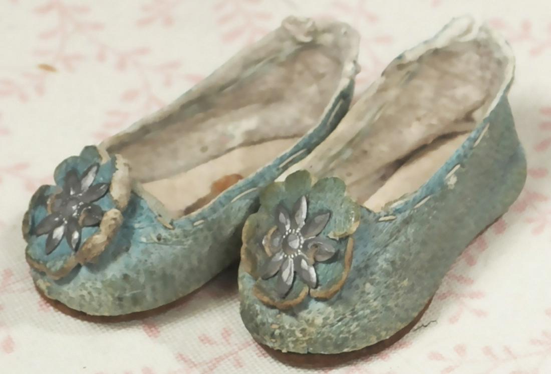 SIZE ONE BLUE LEATHER FRENCH BEBE SHOES.: SIZE ONE BLUE LEATHER FRENCH BEBE SHOES. Marks: Impressed “ 1 star symbol Paris Depose”, 1 1/2" L. pale blue leather slippers with scalloped edge rosettes decorated with eight-point sparkling star