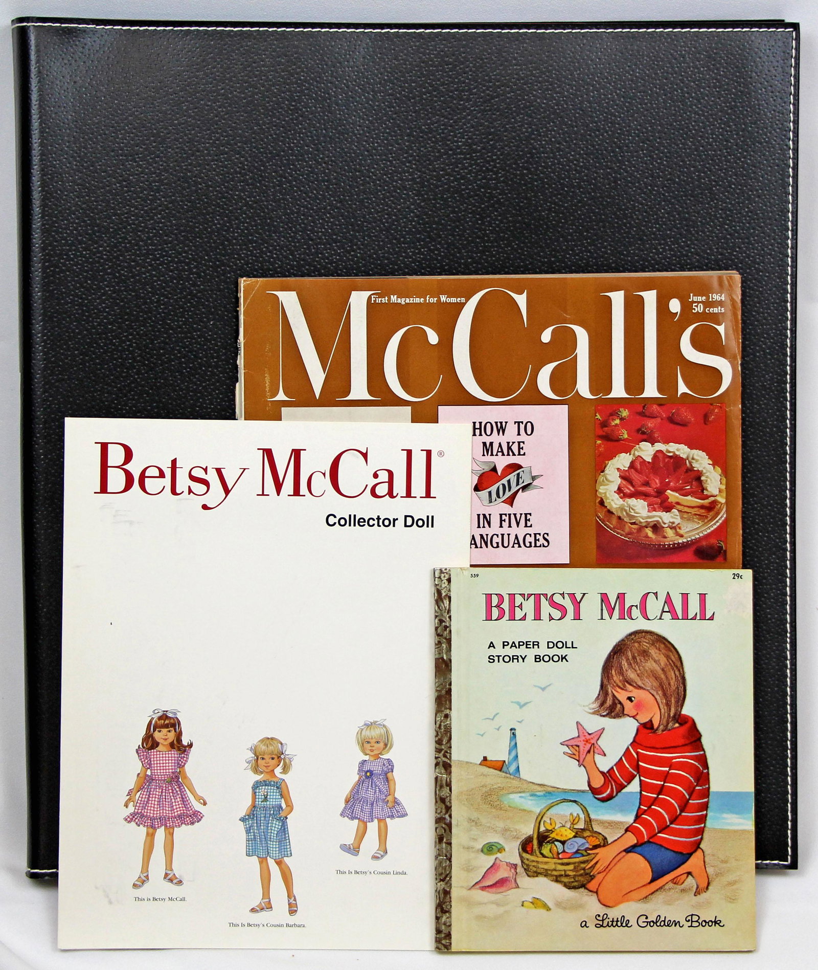 LARGE LOT OF BETSY MCCALL PAPER DOLLS, BLACK LEATHER: LARGE LOT OF BETSY MCCALL PAPER DOLLS, BLACK LEATHER FOLIO, 2 BOOKS. Includes original cardstock dolls of Betsy, her daddy, her mother, and her cousin Barbara (with original mailing envelope and stamp