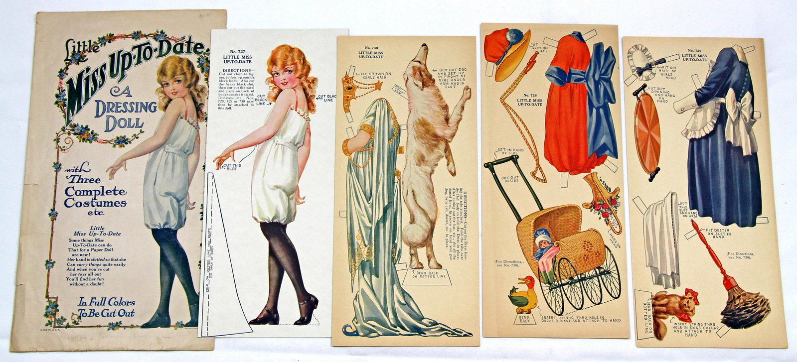 FOUR PAPER DOLLS FROM AMERICAN COLORTYPE WITH SLOTTED: FOUR PAPER DOLLS FROM AMERICAN COLORTYPE WITH SLOTTED HANDS. One uncut 13" doll Little Miss Up to Date with with three complete uncut costumes and envelope; One uncut 13" Little Willie Wide Awake No 7