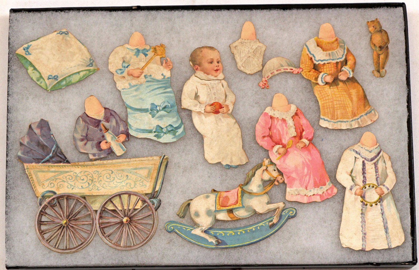 VICTORIAN DIE CUT BABY, GERMAN: VICTORIAN DIE CUT BABY, GERMAN. 4" paper doll baby in reclining position with elaborate christening gowns, jacket, carriage, reclining horse, bib, bonnet, pillow, and bear. " Commentary: Very good ove