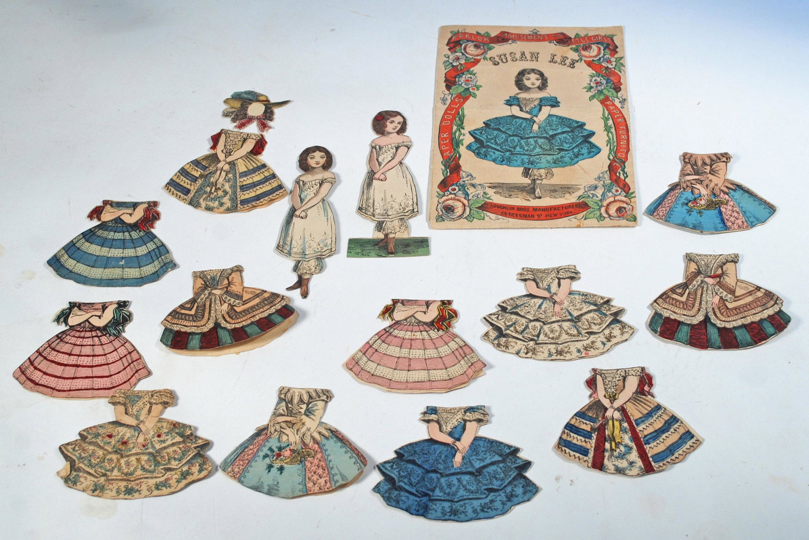 TWO MCLOUGHLIN "SUSAN LEE" PAPER DOLLS: TWO MCLOUGHLIN "SUSAN LEE" PAPER DOLLS. Includes two 4 3/4" paper dolls with slightly different poses; plus twelve costumes, one bonnet, and one original envelope with 1858 patent date. Commentary: Al