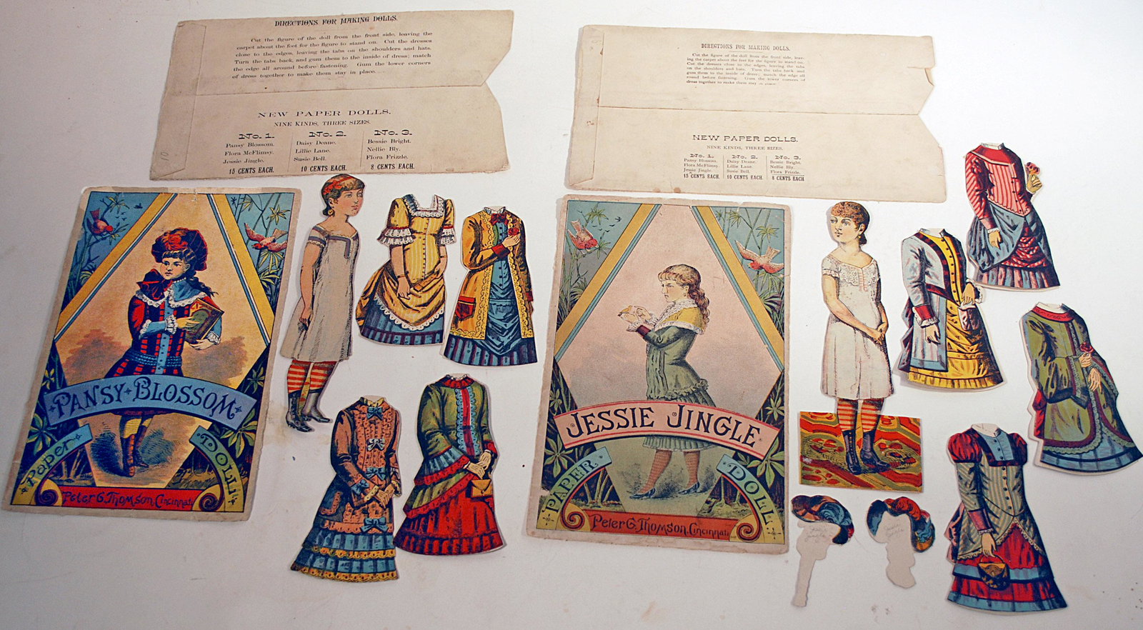 1880 PAPER DOLLS "JESSIE JINGLE & PANSY BLOSSOM" BY: 1880 PAPER DOLLS "JESSIE JINGLE & PANSY BLOSSOM" BY PETER THOMPSON. 7 3/4" -8" dolls. Each two-sided doll posed with slightly turned head; Pansy Blossom has four double-sided costumes, envelope with i
