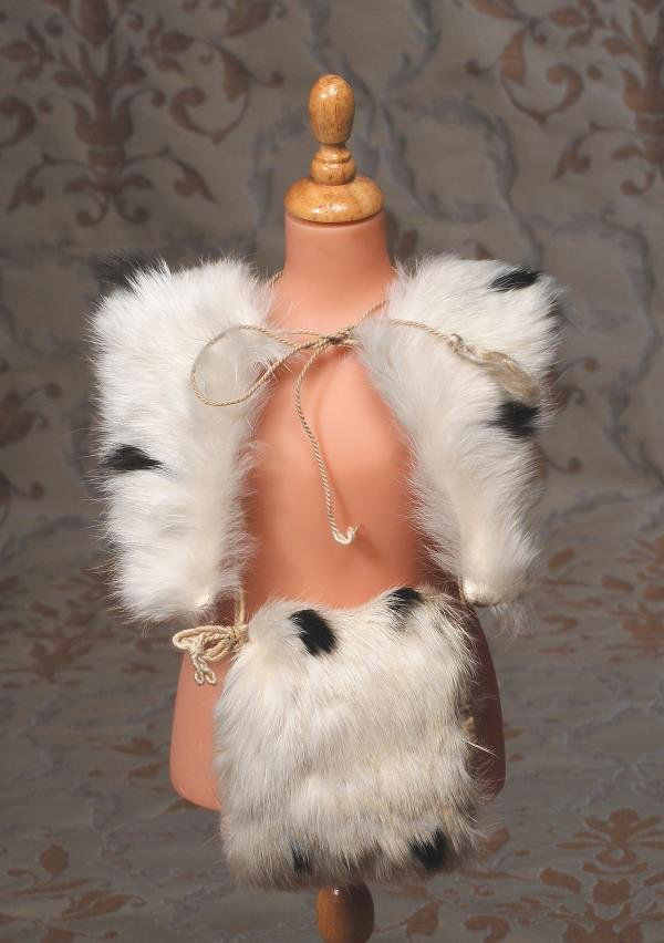 ANTIQUE FUR DOLL'S COLLAR AND MUFF. 10" L. x 7": ANTIQUE FUR DOLL'S COLLAR AND MUFF. 10" L. x 7" W. collar; 4" H. x 3 ½" W. muff. Each of white long-haired fur with black "ermine" look, cotton sateen lining, ivory cord ties and muff loop. Commentar