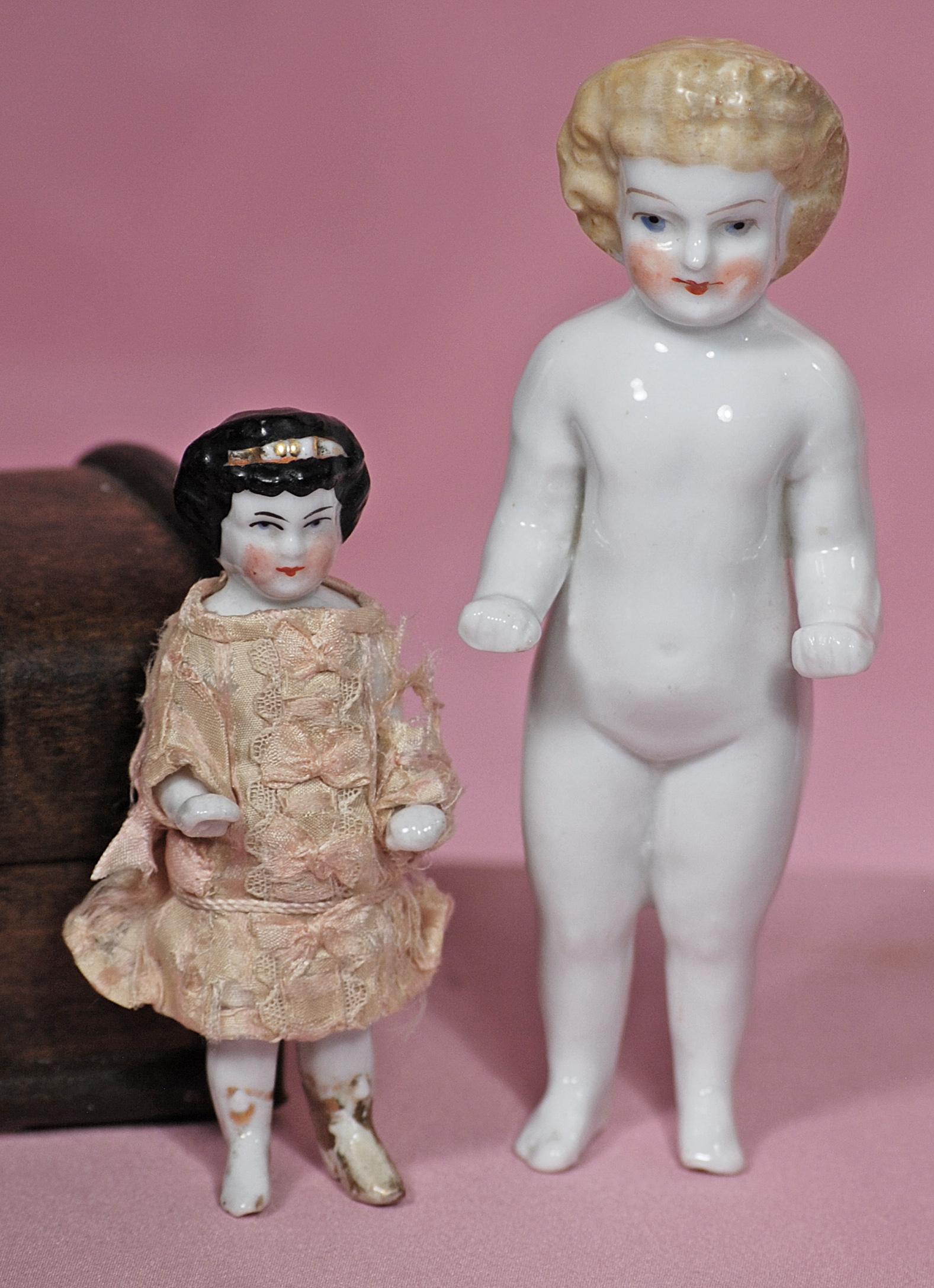 TWO GERMAN PORCELAIN FROZEN CHARLOTTES: TWO GERMAN PORCELAIN FROZEN CHARLOTTES. Each is one-piece porcelain figure with sculpted hair and painted features; 4" doll has black haired doll has gilt headband and boots, pink silk dress; 5" doll 