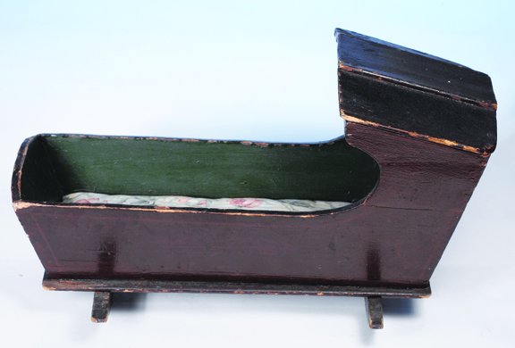 EARLY AMERICAN DOLLS HOODED CRADLE. 17" l. Wooden: EARLY AMERICAN DOLLS HOODED CRADLE. 17" l. Wooden cradle with hooded top composed of fitted slats, shaped rockers, original finish, painted dark green interior. Commentary: Mid-19th century, very good