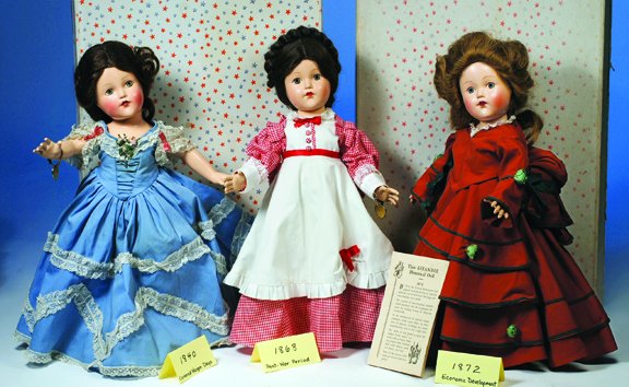 EFFANBEE 1868 POST WAR PERIOD. Green eyes, dark b: EFFANBEE 1868 POST WAR PERIOD. Green eyes, dark brown wig with hair waved back and encircled by braids, red and white check dress with white apron, petticoat, pantaloons, wrist bracelet. Commentary: B