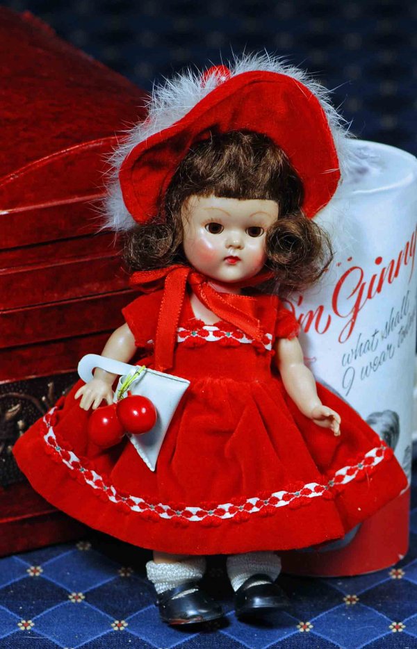 VOGUE 1953 DOLL "GINGER" IN RED VELVET: VOGUE GINNY HARD PLASTIC DOLL “GINGER: FROM THE DEBUTANTE SERIES. 8”. Marks: Vogue Doll. All-hard plastic walker, brown sleep eyes, painted lashes, brunette wig, tagged deep red velvet dress with