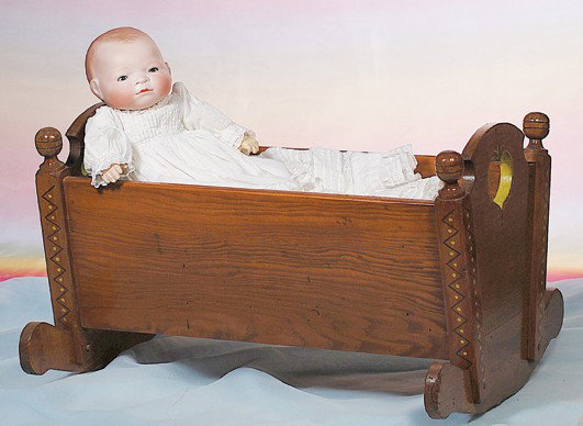 GERMAN BISQUE BYE-LO BABY WITH CRADLE. Marks: Cop: GERMAN BISQUE BYE-LO BABY WITH CRADLE. Marks: Copr. Grace S. Putnam. 12 ½" head circumference. Bisque swivel head, molded and painted curly brown hair, blue sleep eyes, painted lashes, tinted brows, 