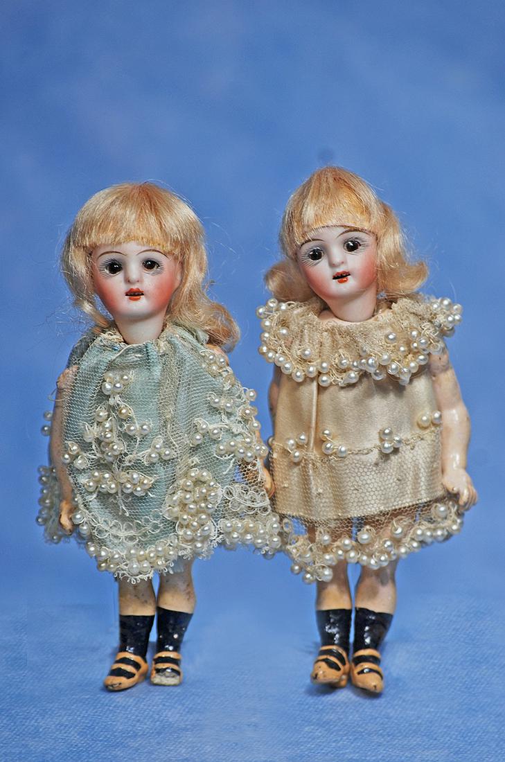 PAIR OF MINIATURE BISQUE DOLLS: 181. PAIR OF MINIATURE BISQUE DOLLS. 5”. Marks: 310. Each has bisque socket head, stationary brown glass eyes, painted lashes, tapered brows, open mouth, upper teeth, original blonde mohair wig,