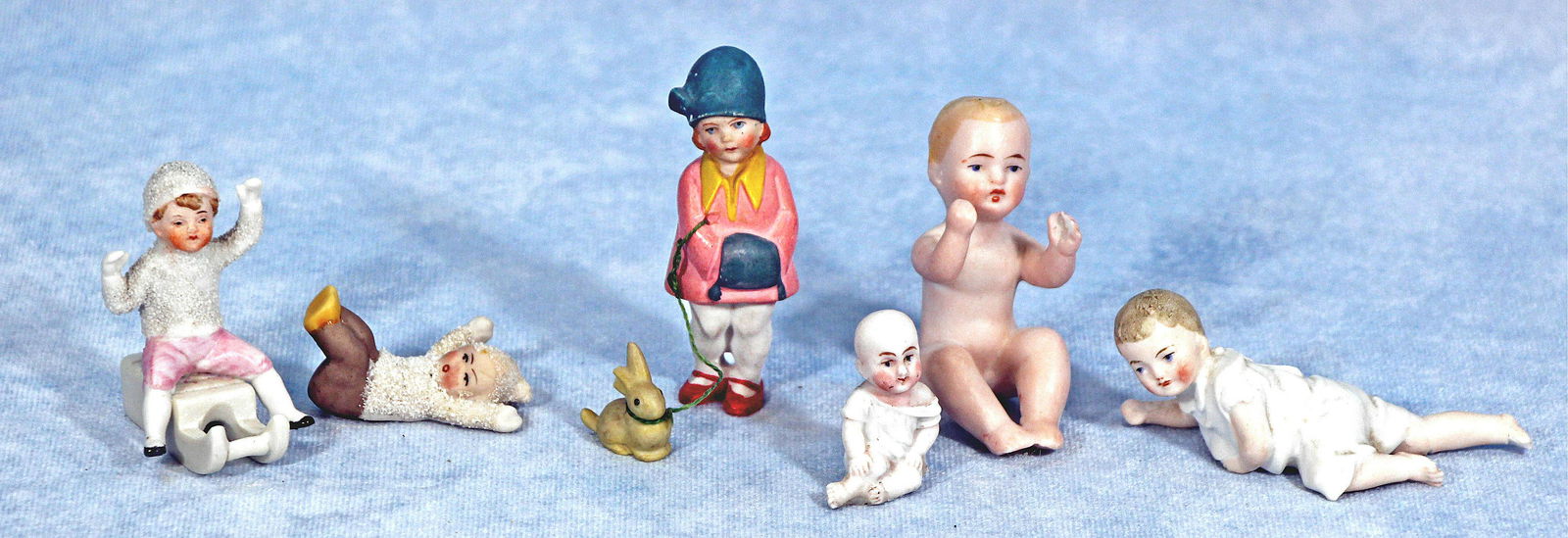ALL BISQUE, SNOW BABIES, AND MORE: 298. ALL BISQUE, SNOW BABIES, AND MORE. Lot includes two snow babies: 2 1/4" with pink pants sitting on sled, arms up, marked 8721 Germany and one 1 3/4" in sitting position with brown pants; One sitt