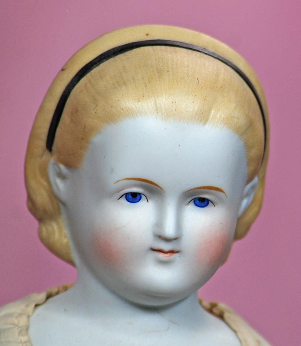 GERMAN BISQUE LADY WITH "ALICE" COIFFURE: 11. GERMAN BISQUE LADY WITH "ALICE" COIFFURE. 17 ½”. Bisque shoulderhead with sculpted blonde hair pulled away from face and secured by black headband, fully-modelled ears, painted features, outlin