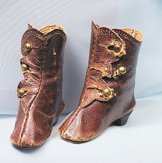 PAIR OF BROWN LEATHER FASHION DOLL BOOTS: 2 ¼" L. Dark brown leather boots with narrow styling, leather soles and black wooden heels, three-button side closing, stitched edges. Commentary: One boot has break at button hole, otherwise good co
