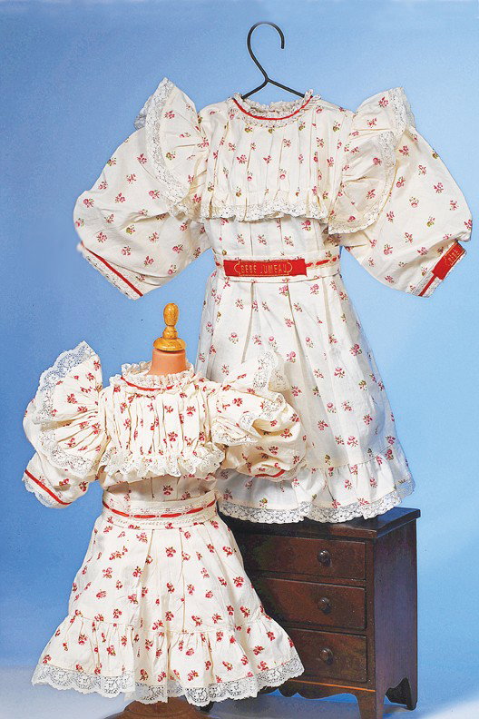 TWO RED-FLOWERED CHEMISES FOR BEBE JUMEAU: White muslin printed with tiny red flowers has accordion pleated bodice and hem ruffle, lace edging, white lace at collar, full short sleeves, box-pleated front from below the bodice, matching separat
