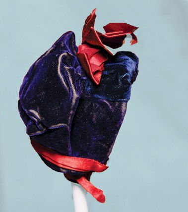 ANTIQUE VELVET DOLL BONNET. Dark blue velvet gathe: ANTIQUE VELVET DOLL BONNET. Dark blue velvet gathered over wire brim has softly gathered back, ruby red silk ribbon ties and bows accenting the top, ivory silk lining, 2 ¾" wide inside cap. Commentar