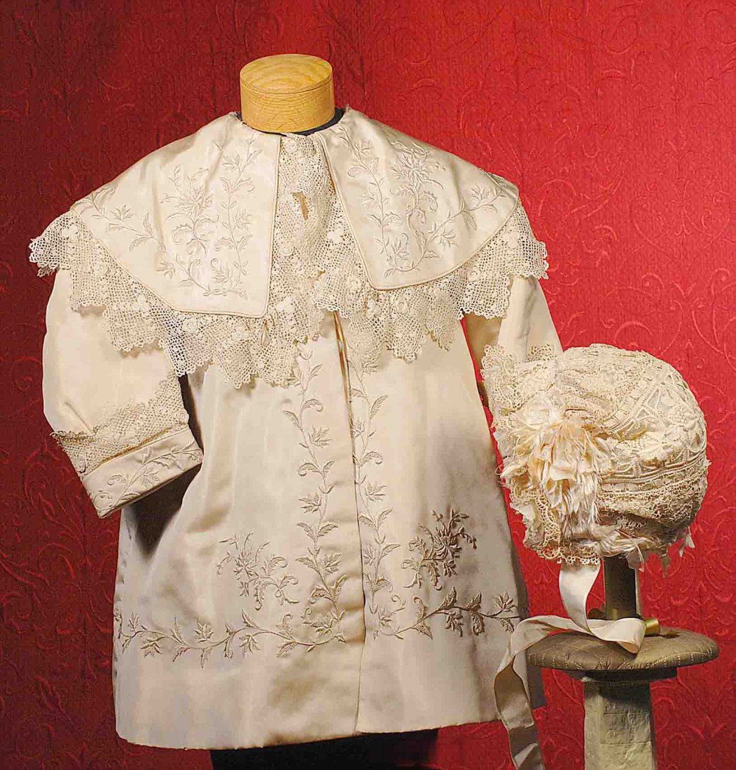 ANTIQUE IVORY SILK COAT WITH EMBROIDERY.: ANTIQUE IVORY SILK COAT WITH EMBROIDERY. 11” shoulder width; 22” length. Ivory silk coat features luxuriously-embroidered detail all around the coat as well as the 5 ½” deep Vandyke collar and 