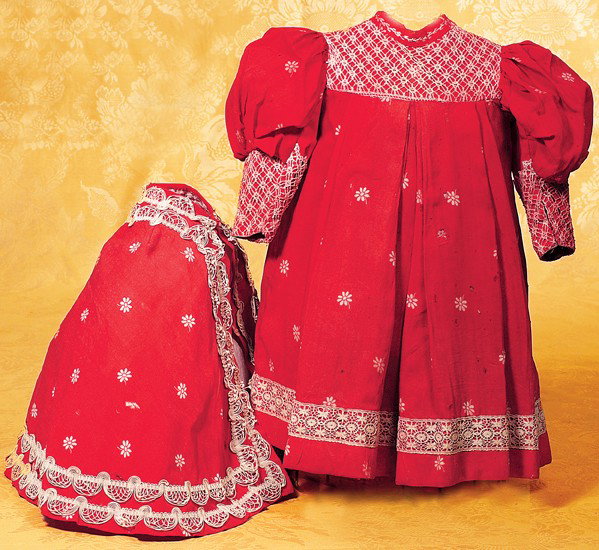 ANTIQUE BEBE JUMEAU COSTUME: ANTIQUE BEBE JUMEAU COSTUME. 7" shoulder width, 17 ½" length. Very fine red cotton fabric with white daisy designs, lace-covered inset yoke, gathered and poufed sleeves with fitted lower arms covered