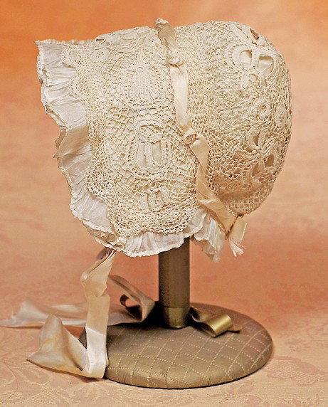 ANTIQUE LACE AND SILK DOLL BONNET: ANTIQUE LACE AND SILK DOLL BONNET. Fine ivory embroidered lace with scalloped edge, double silk ruffles at brim, silk ribbon and rosette accenting the crown with bow at back, silk lining and ribbon ti