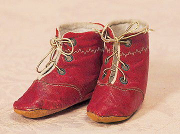 PAIR OF ANTIQUE RED LEATHER DOLL BOOTS: PAIR OF ANTIQUE RED LEATHER DOLL BOOTS. 3" L. Rich red leather boots are lined in white cotton fabric and are decorated with ivory stitching detail, lace-up style with metal grommets, leather soles. C