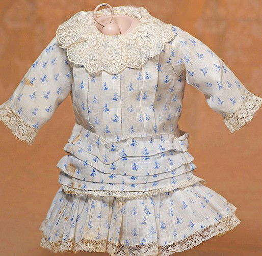 ANTIQUE BLUE AND WHITE COTTON DRESS FOR BEBE: ANTIQUE BLUE AND WHITE COTTON DRESS FOR BEBE. 5" shoulder width; 11" length. Fine white cotton frock with dainty blue flower pattern, dropped waist, vertical bodice tucks, inset sleeves, lace trim at