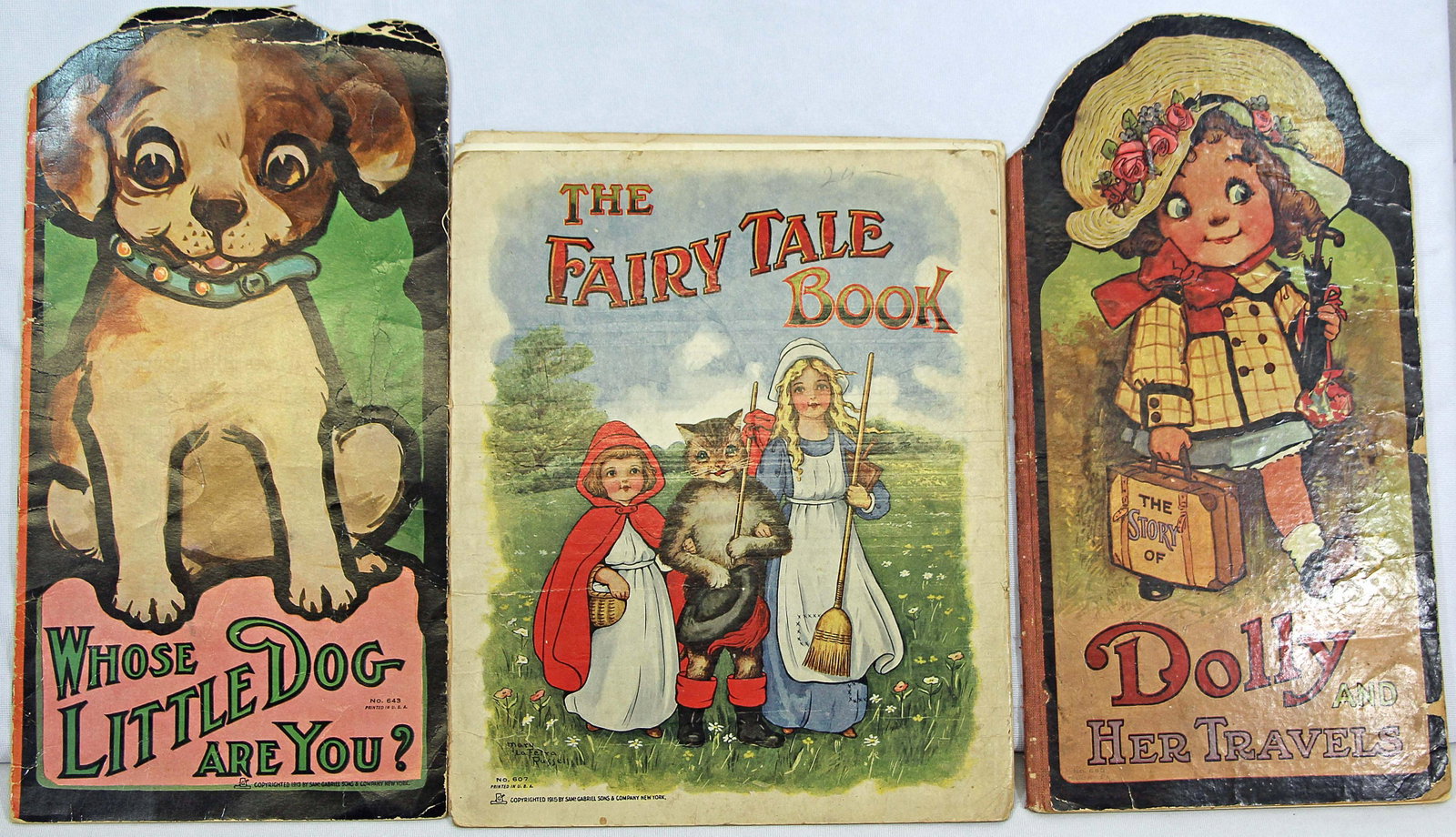 THREE BOOKS BY SAMUEL GABRIEL & SONS: 55. THREE BOOKS BY SAMUEL GABRIEL & SONS. Two 14 1/2" x 7 1/2" die cut books: "Whose Little Dog Are You? " No 643, copyright 1913 (softcover and minor bend at top) and "The Story of Dolly and Her Trav