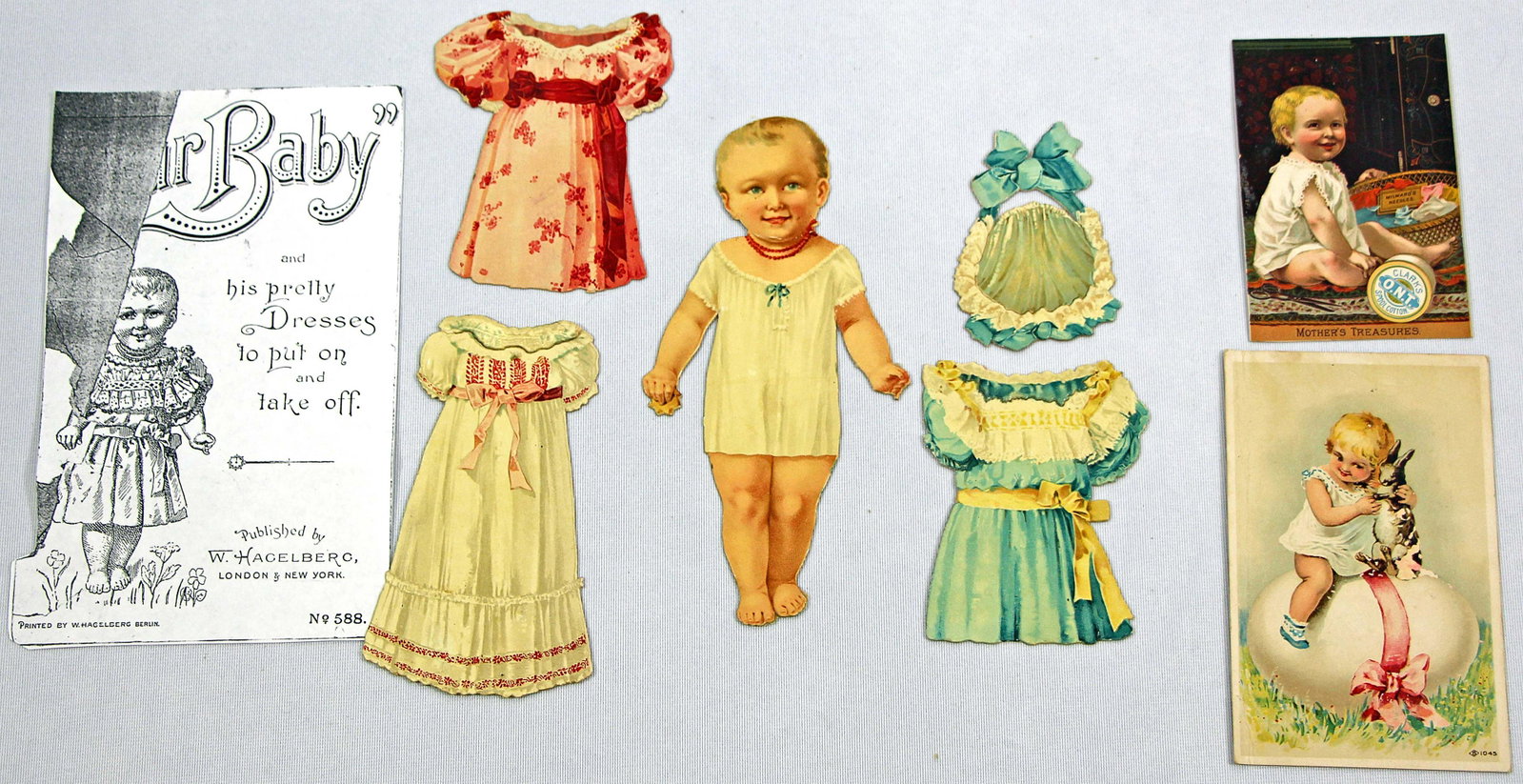 OUR BABY HAGELBERG PAPER DOLL AND 2 ADVERTISEMENT CARDS: 64. OUR BABY HAGELBERG PAPER DOLL AND 2 ADVERTISEMENT CARDS. 7" engraved baby paper doll with 3 dresses and one hat, has front copy of envelope titled "Our Baby and his pretty Dresses to put on and ta