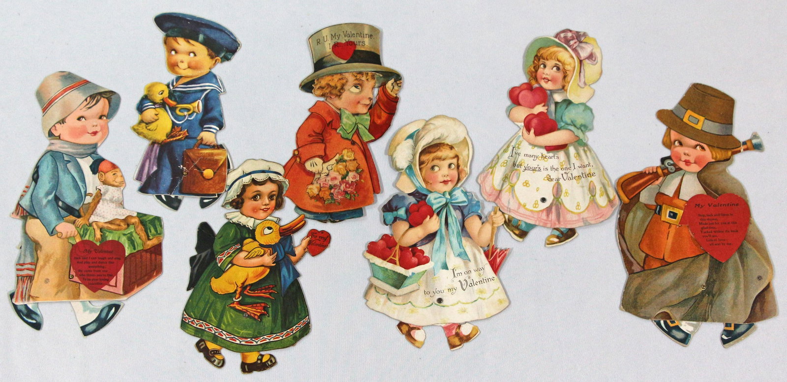 SEVEN VALENTINE GREETING WALKING DOLLS.: 126. SEVEN VALENTINE GREETING WALKING DOLLS. 7" to 9" tall. All dolls have walking mechanism; Three are printed in Germany, circa 1920s (the two girls holding hearts and the girl holding a duck). Boy 
