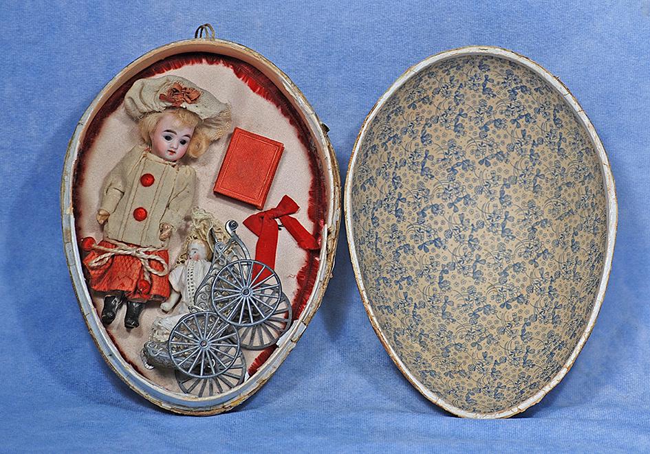 MINIATURE BISQUE DOLL IN PRESENTATION EGG. Doll 5”; Egg 8”. Paper mache floral-covered: MINIATURE BISQUE DOLL IN PRESENTATION EGG. Doll 5”; Egg 8”. Paper mache floral-covered egg contains a bisque socket head doll with stationary blue glass eyes, painted lashes, open mouth, u