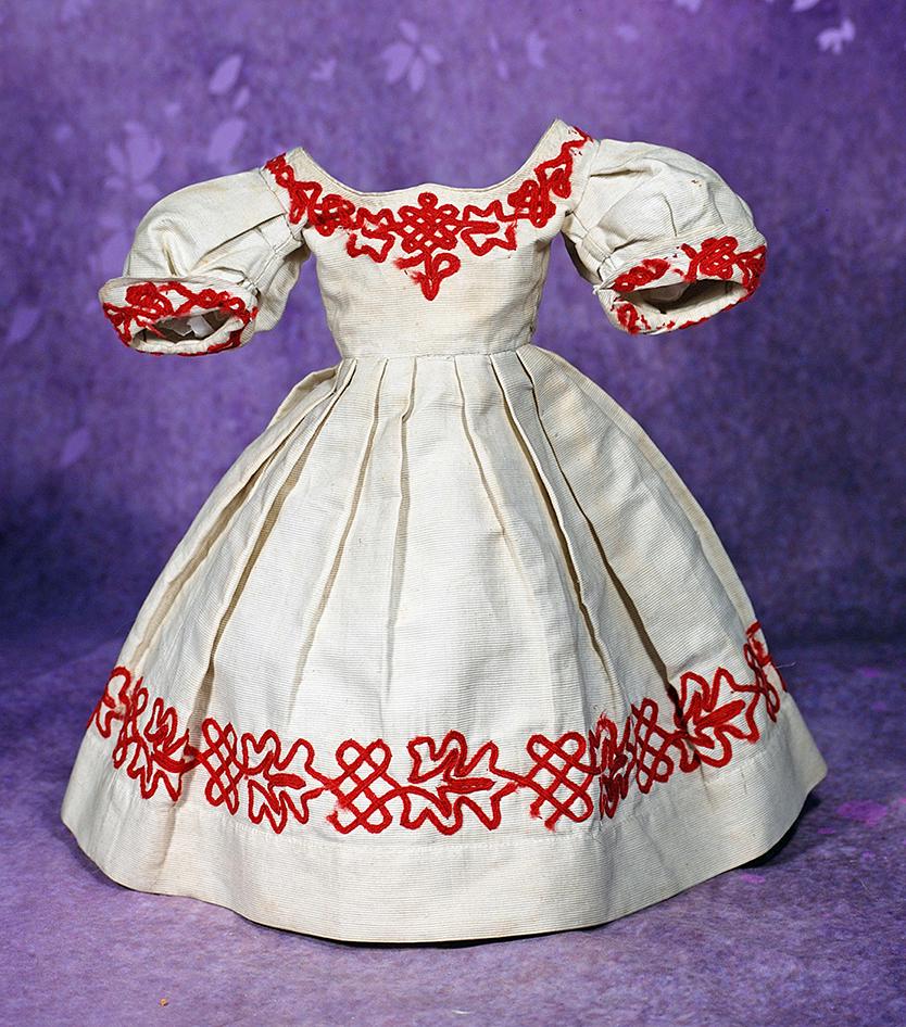 FINE ANTIQUE GOWN FOR POUPEE WITH RED SOUTACHE TRIM. 4” shoulder width, 12 ½”: FINE ANTIQUE GOWN FOR POUPEE WITH RED SOUTACHE TRIM. 4” shoulder width, 12 ½” length, 7 ½” waist. Ivory pique gown with rounded bodice, poufed and pleated short sleeves, sh