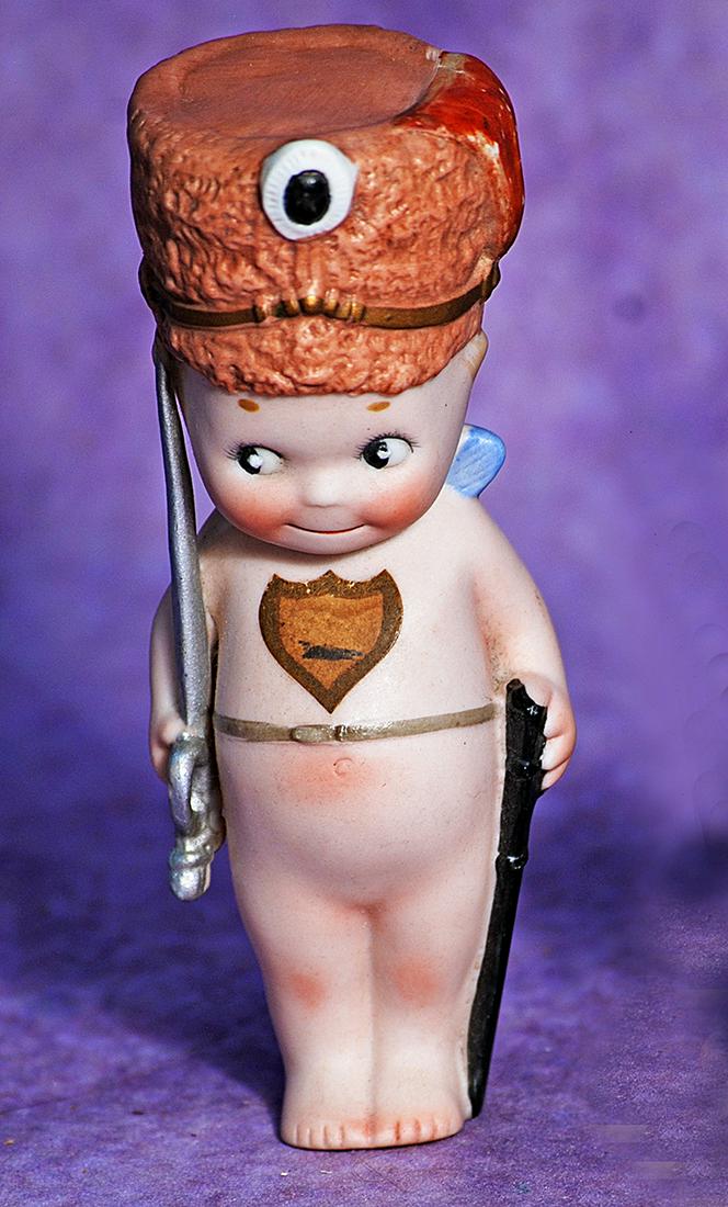 GERMAN BISQUE KEWPIE WITH HELMET. 5”. Marks: O’Neill copyright sticker on back. One: GERMAN BISQUE KEWPIE WITH HELMET. 5”. Marks: O’Neill copyright sticker on back. One piece classic standing Kewpie with jointed arms, side-glancing googly eyes, blue wings, and with very fa