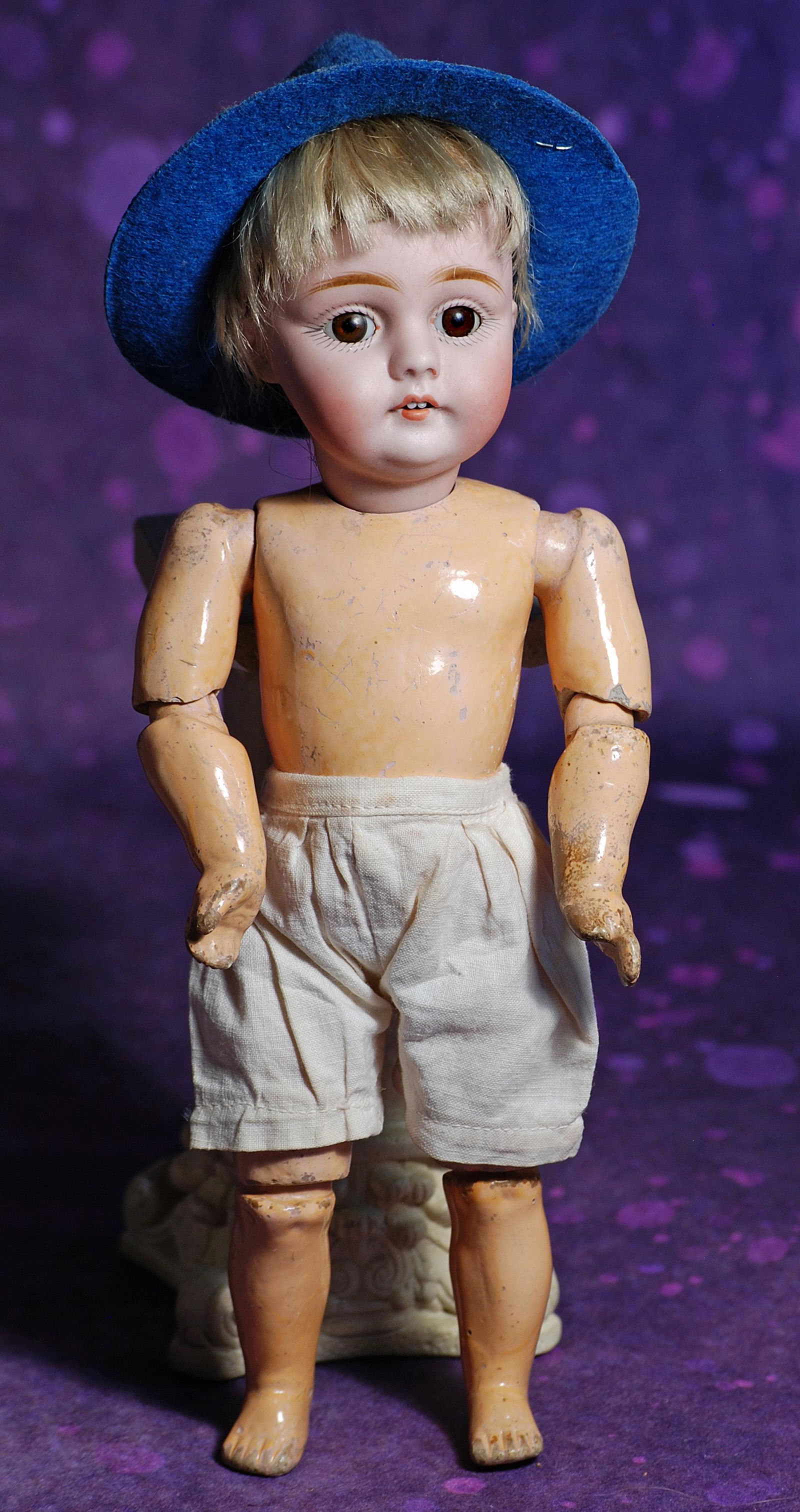 PETITE GERMAN BISQUE, MODEL 143, BY KESTNER. 9 ½”. Marks: made in Germany 143. Bisque: PETITE GERMAN BISQUE, MODEL 143, BY KESTNER. 9 ½”. Marks: made in Germany 143. Bisque socket head, brown sleep eyes, painted lashes, feathered brows, open mouth, two upper teeth, sparse blo