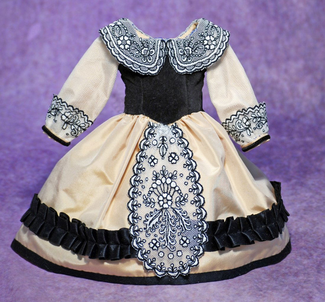 SILK AND VELVET DOLL DR: FINE SILK AND VELVET DOLL DRESS. Cream silk gown with black velvet fitted bodice, rounded neckline, long sleeves, gathered skirt with black silk ribbon pleated trim and edging, silk bow at back, embro