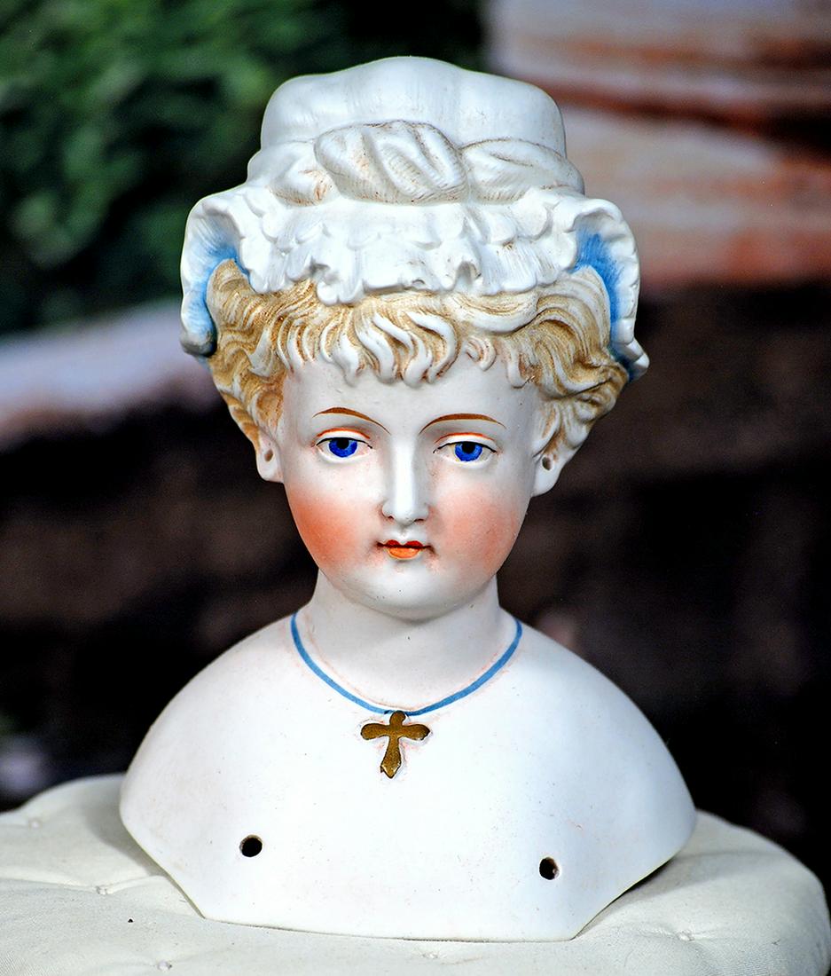 GERMAN BISQUE LADY HEAD WITH SCULPTED BONNET.  5 ½”.  Marks: 16.  Bisque shoulderhead of (1 of 2)