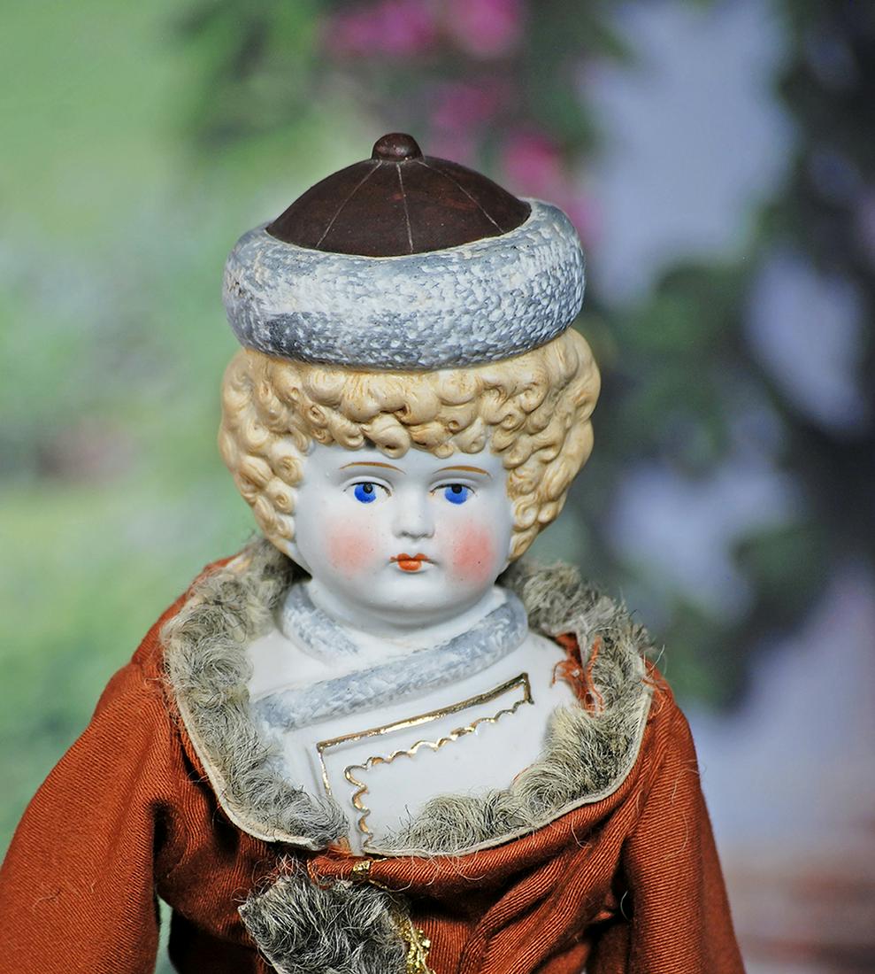 GERMAN BISQUE DOLL WITH SCULPTED BONNET. 16”. Bisque shoulderhead with sculpted brown bonnet: GERMAN BISQUE DOLL WITH SCULPTED BONNET. 16”. Bisque shoulderhead with sculpted brown bonnet with gray fur trim over sculpted blonde hair in ringlet curls, painted features, blue eyes, tapered b