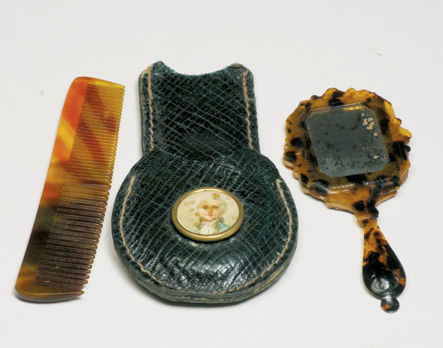RARE MINIATURE TORTOISE SHELL HAND-MIRROR & COMB: RARE MINIATURE TORTOISE SHELL HAND-MIRROR & COMB IN LEATHER CASE. Case 3”. Ornate tortoise shell frame and handle, dark red paper backing, plus tortoise shell comb; embossed dark green leather case