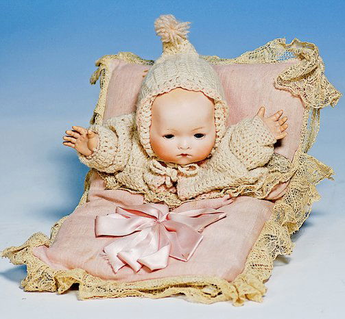 GERMAN BISQUE “PILLOW BABY” IN ORIGINAL PRESENTAT: GERMAN BISQUE “PILLOW BABY” IN ORIGINAL PRESENTATION. Marks: Germany, Kiddiejoy. 10” x 7”. Solid-domed bisque head baby with flange neck, painted hair, blue glass eyes, closed mouth, presented