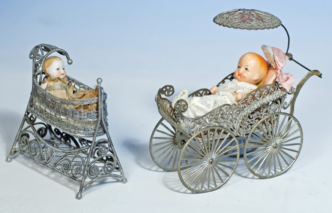 ANTIQUE MINIATURE DOLL CRADLE & FILIGREE CARRIAGE: ANTIQUE MINIATURE DOLL CRADLE & FILIGREE CARRIAGE. 5” H. silver-finish woven swinging cradle with scrolled base and hood, holds miniature German all-bisque baby in original gauze gown; 6” ornately