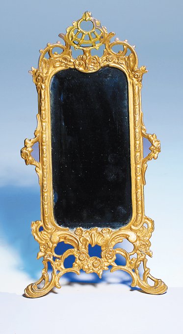 VERY ORNATE GILT TABLE MIRROR WITH BEVELED GLASS.: VERY ORNATE GILT TABLE MIRROR WITH BEVELED GLASS. 14 ½” H. Metal with rich ornamental detail and painted gilt finish, beveled mirror, attached metal back for standing. Commentary: Late 19th century