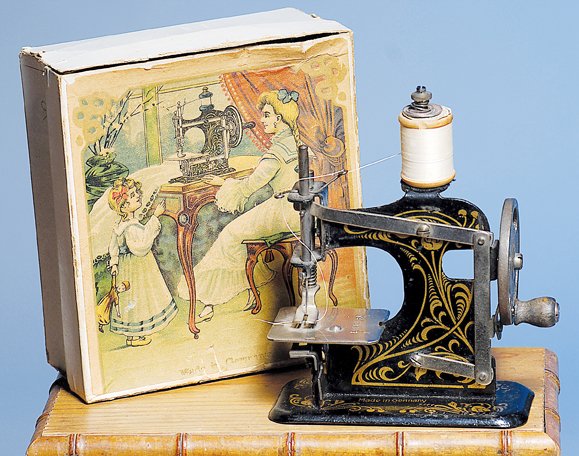 GERMAN TOY SEWING MACHINE IN ORIGINAL BOX. 4 ¼”. : GERMAN TOY SEWING MACHINE IN ORIGINAL BOX. 4 ¼”. Tin metal toy sewing machine with gold fancy stenciled designs, includes metal clamp for fastening to table top; preserved in original box with chro