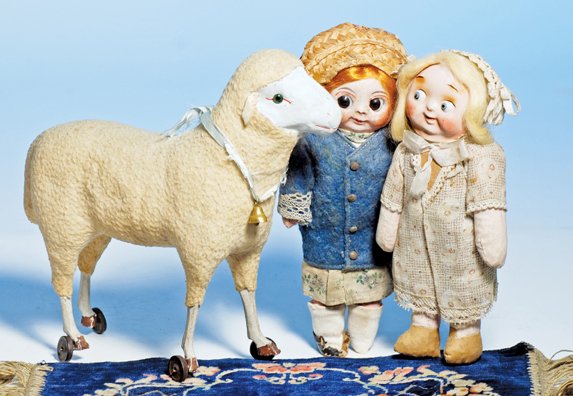 GERMAN WOOL-COVERED LAMB ON WHEELS. 9 ½” H. Molde: GERMAN WOOL-COVERED LAMB ON WHEELS. 9 ½” H. Molded papier mache lamb has painted face with green glass eyes, leather ears, wool-covered body, painted wooden legs, feet attached to metal rollers, vo