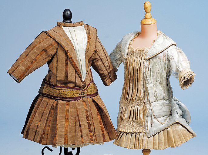 ANTIQUE BLUE AND BEIGE SILK FROCK BY BRU WORKSHOP: ANTIQUE BLUE AND BEIGE SILK FROCK BY BRU WORKSHOP. 5” shoulder width; 10" length. Ice blue silk dress features jacket top with shirred beige silk plastron, flared collar and side pockets with piping
