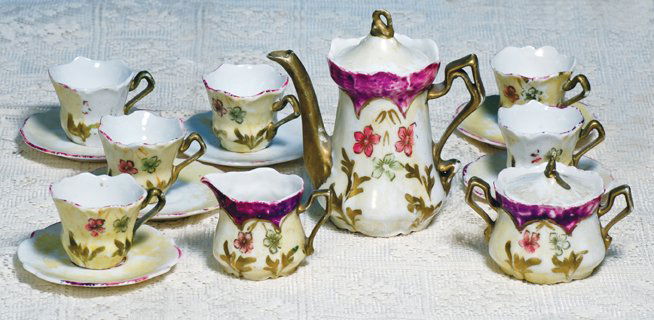 ANTIQUE DOLL-SIZED TEA SET WITH RICH DECORATION.: ANTIQUE DOLL-SIZED TEA SET WITH RICH DECORATION. Seventeen piece set includes 5” H. lidded teapot, lidded sugar bowl, creamer, six cups and six saucers; teapot, creamer and sugar with decorated mage