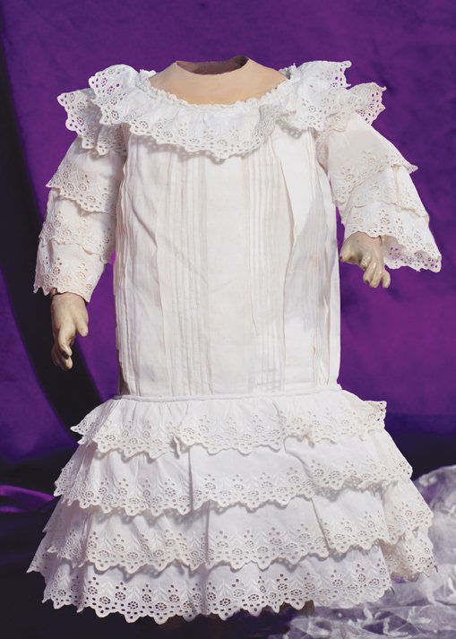 ANTIQUE WHITE COTTON FROCK: ANTIQUE WHITE COTTON FROCK. 7” shoulder width, 16” length. White cotton with dropped waist and rounded neckline with eyelet ruffle, three-tiered eyelet sleeves, vertical stitched tucks and folds a